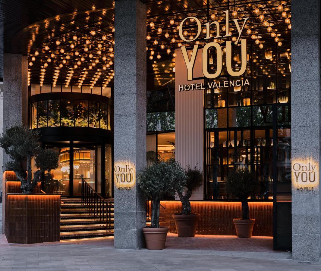 Only You Hotel Valencia Ngoại thất bức ảnh The photo shows the entrance of a hotel named "Only YOU Hotel Valencia." The facade is modern and stylish, featuring a large, well-lit sign with the hotel name prominently displayed. The entrance is adorned with decorative lighting overhead, creating